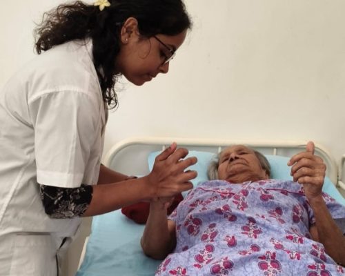 Caregiver Assisting Elderly Patient In Hospital Bed